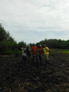 Five people covered in dirt holding tools
