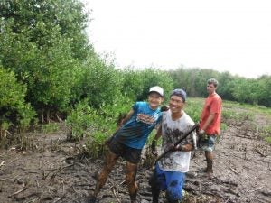 Three people covered in dirt holding tools