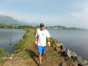 Man walking on peninsula surrounded by ocean