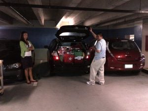 man loading items in to car while woman looks on