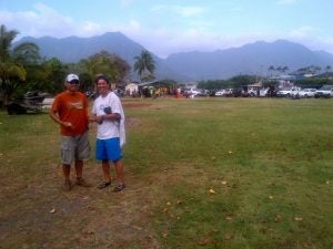 Two men posing in front of parking lot