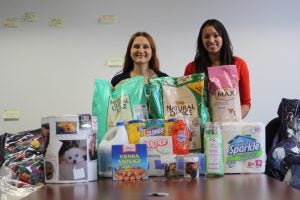 two women smiling in front of pet food
