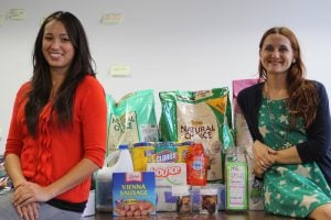 two women smiling in front of pet food