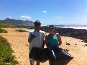 photo+2 Man and woman holding trash bags on beach